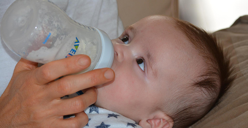 A baby drinks from a bottle.